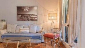 Ein Wohnzimmer mit einer Couch, einem Sessel, einer Lampe und einem Gemälde an der Wand.