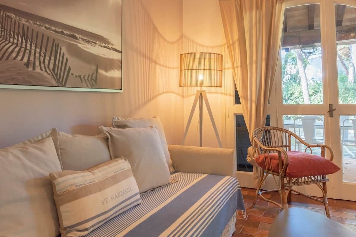 A room with a bed, a chair, a lamp, and a door leading outside.