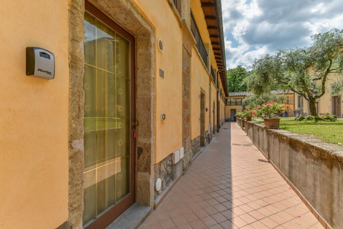 Un corridoio con pavimento piastrellato, una porta in vetro e un dispositivo fissato al muro.
