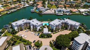 A marina with boats docked, a central swimming pool, and a building with a symmetrical design. - South End Waterfront Condo | Walk to Beach (Marco Island)