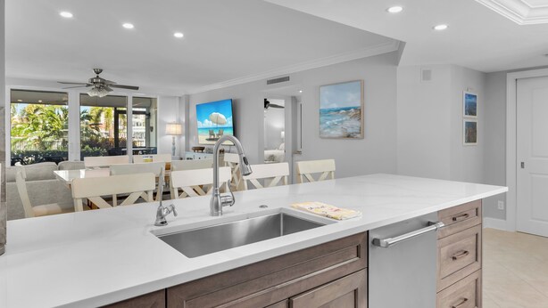 A modern kitchen with a white countertop, stainless steel sink, and wooden cabinets. - South End Waterfront Condo | Walk to Beach (Marco Island)