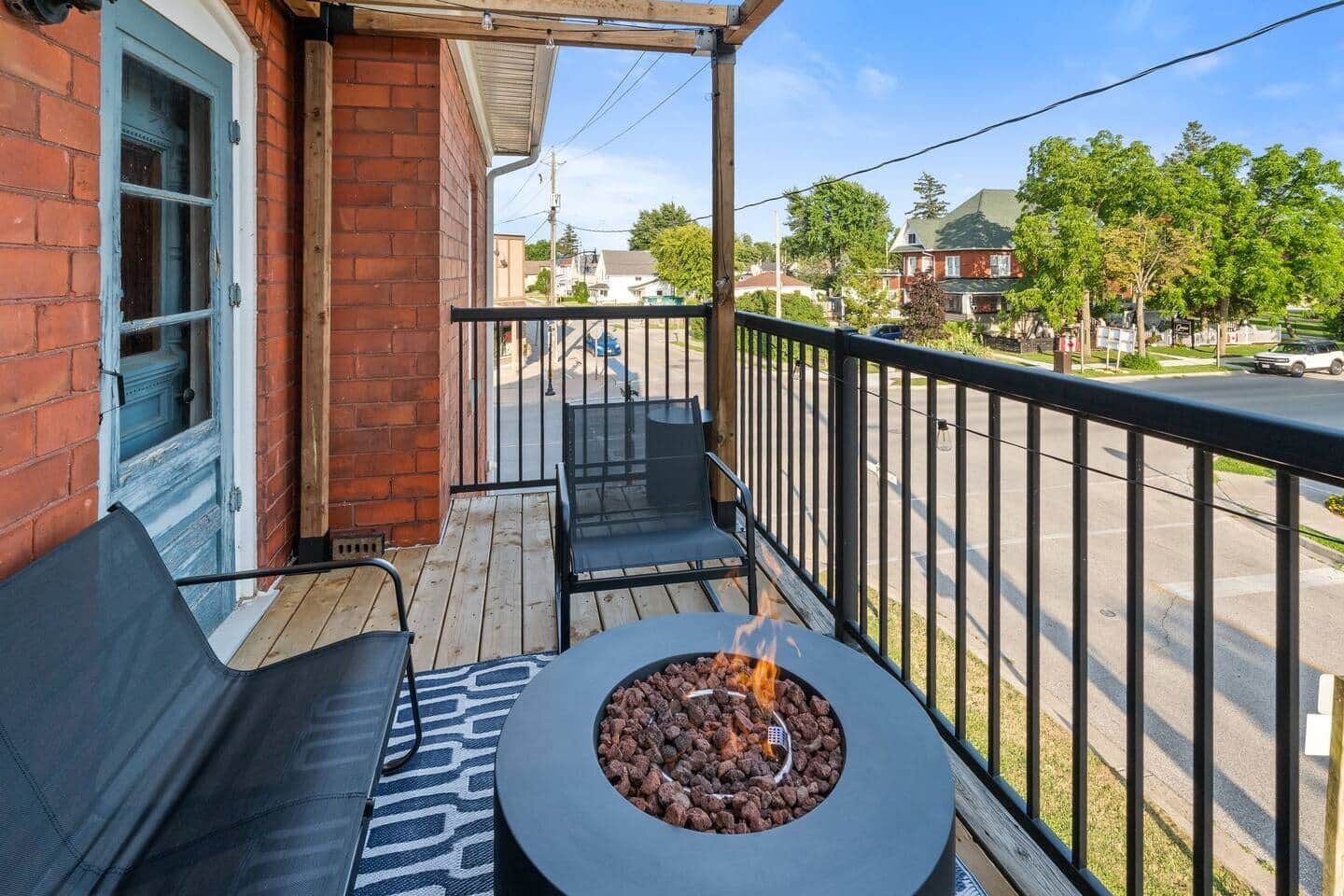 Un balcon avec un foyer extérieur, des sièges pour profiter de l’extérieur et une vue sur la rue.