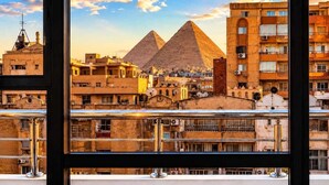 A view of the pyramids through a window with a metal railing. - Grand Pyramids Hotel (Giza)