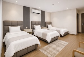 A modern hotel room with three beds, a large window, and a built-in air conditioning unit. - Grand Pyramids Hotel (Giza)