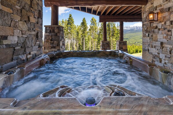 A hot tub with a view of a forest and mountains.