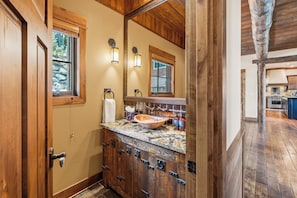 A bathroom with a wooden vanity, a large mirror, and a stone sink.