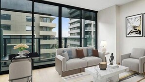 A modern living room with a sofa set, a coffee table, and a dining area with a glass table. - Yarra Luxe on Chapel Street by SAGA stays (South Yarra)