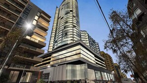 A modern high-rise building with a curved facade, large windows, and a prominent entrance. - Yarra Luxe on Chapel Street by SAGA stays (South Yarra)
