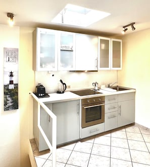 Una cocina compacta con horno integrado, cafetera y lavabo.