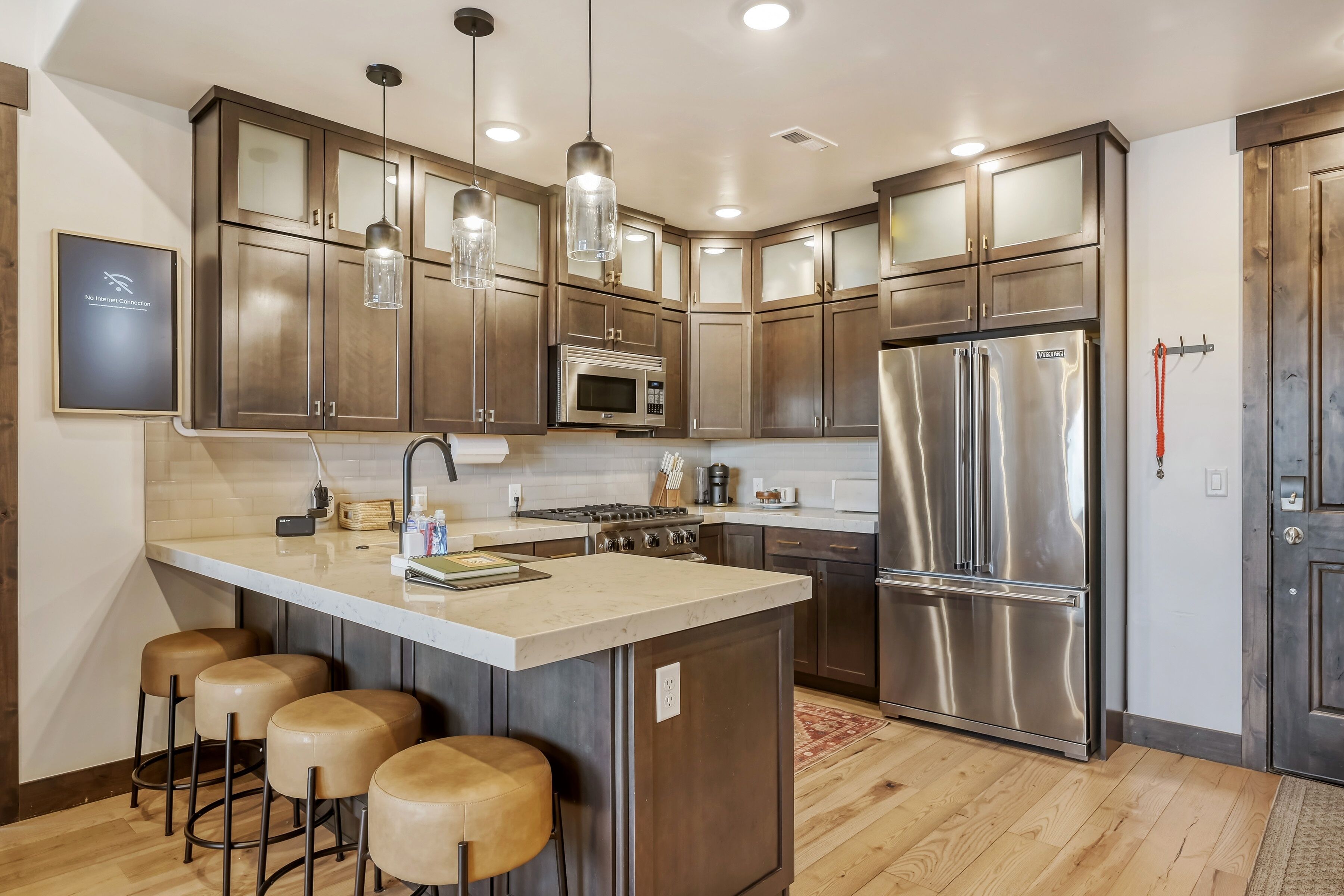 Una cocina moderna con electrodomésticos de acero inoxidable, armarios de madera y una isla central con taburetes.