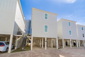 A row of white buildings with multiple parking spaces and a covered walkway. - Endless Summer 161 4 Bedroom Home (Gulf Shores)