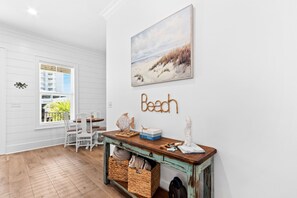 A beach-themed room with a white wall, a painting of a beach scene, and a word 'Beach' spelled out in rope letters. - Endless Summer 161 4 Bedroom Home (Gulf Shores)