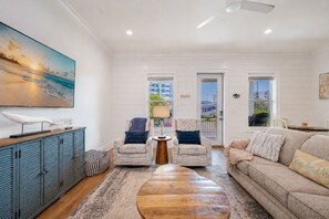 A spacious living room with a large painting, a wooden coffee table, two armchairs, a sofa, and a cabinet. - Endless Summer 161 4 Bedroom Home (Gulf Shores)