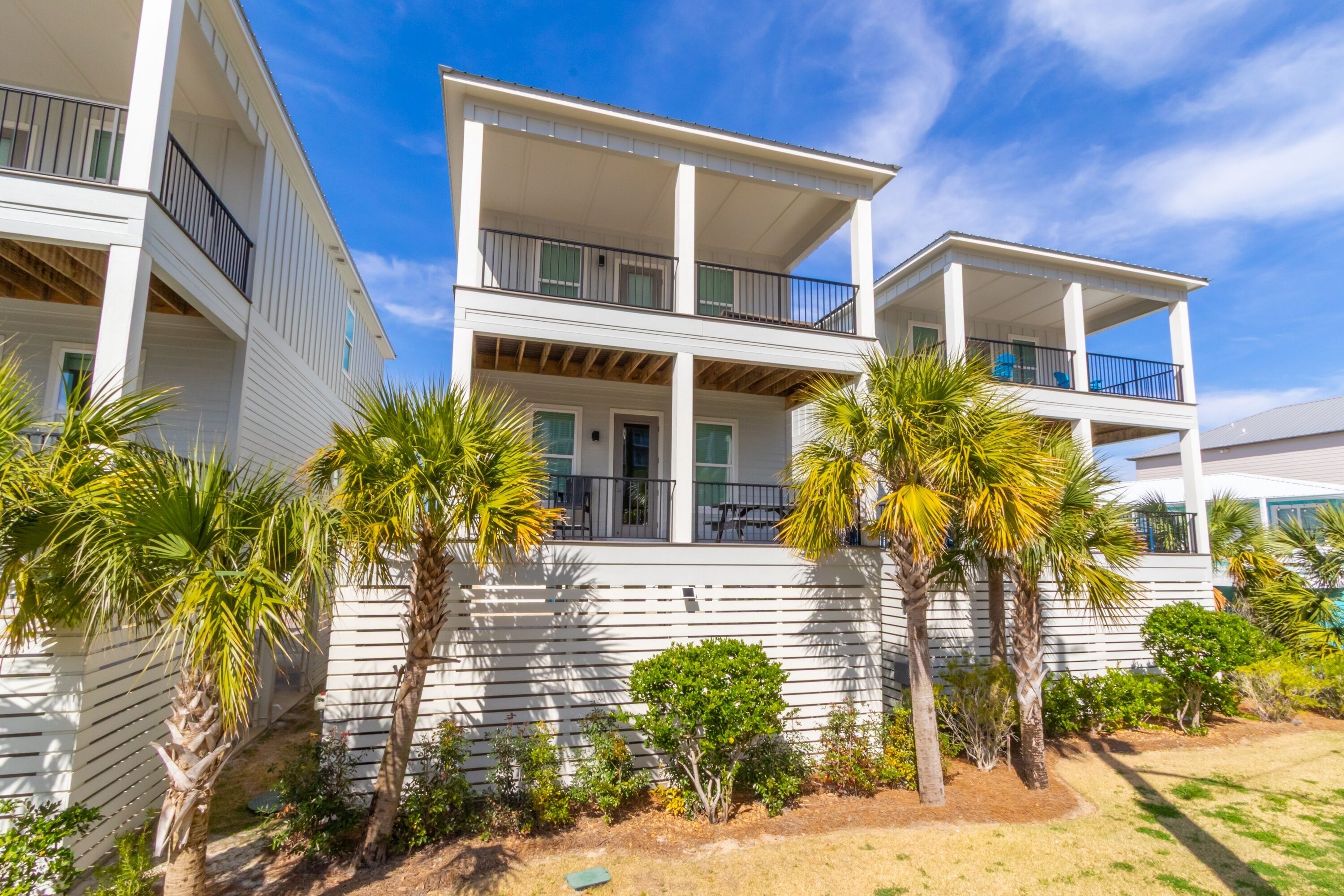 A multi-story building with balconies, palm trees, and a clear sky.