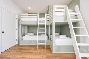 A bunk bed room with a white door, wooden flooring, and a white ladder. - Endless Summer 161 4 Bedroom Home (Gulf Shores)