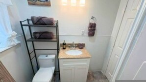 Een kleine badkamer met toilet, wastafel en een plank met handdoeken.