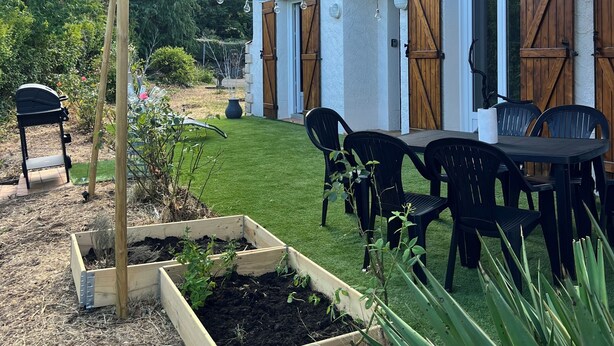 A house with a white exterior, wooden shutters, a garden with a raised bed, and a patio with chairs and a table. - Villa Papillon Clermont-Ferrand, 3-star, for 2 to 6 people, Clermont-Ferrand (Nohanent)