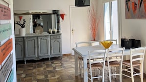 A dining area with a white table and chairs, a black pendant light, and a tiled floor. - Villa Papillon Clermont-Ferrand, 3-star, for 2 to 6 people, Clermont-Ferrand (Nohanent)