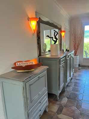 A well-lit hallway with a decorative mirror, a vintage-style dresser, and a potted plant. - Villa Papillon Clermont-Ferrand, 3-star, for 2 to 6 people, Clermont-Ferrand (Nohanent)