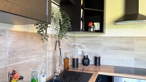 A modern kitchen with a black sink, wooden countertop, stainless steel appliances, and a black range hood. - Villa Papillon Clermont-Ferrand, 3-star, for 2 to 6 people, Clermont-Ferrand (Nohanent)