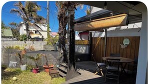A wooden deck with a table and chairs, surrounded by potted plants and a basketball hoop. - Kaz HOLY LAND (Saint-Pierre)