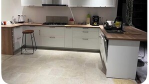 A modern kitchen with white cabinets, a central island, and a built-in dishwasher. - Kaz HOLY LAND (Saint-Pierre)