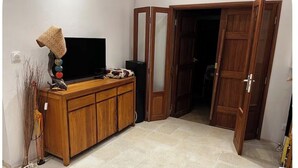 A room with a wooden cabinet, a television, and a door leading to another room. - Kaz HOLY LAND (Saint-Pierre)