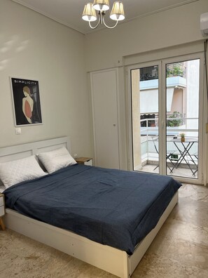 A bedroom with a bed, a nightstand, a poster on the wall, and a sliding glass door leading to an outdoor area. - Sweet & New Studio - Center Athens (Athina)