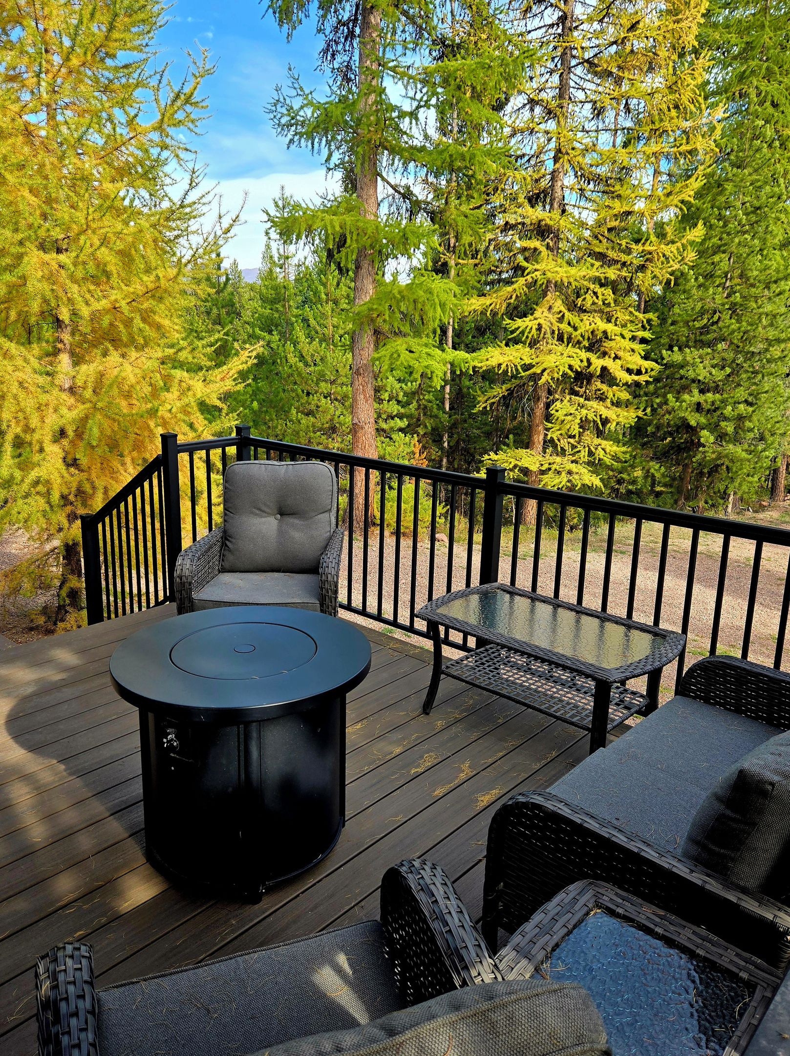 A deck with outdoor furniture, including a round table and chairs, surrounded by a railing.