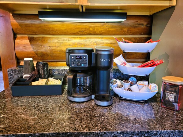 A coffee station with a Keurig coffee maker, a coffee pot, and a bowl of coffee pods.
