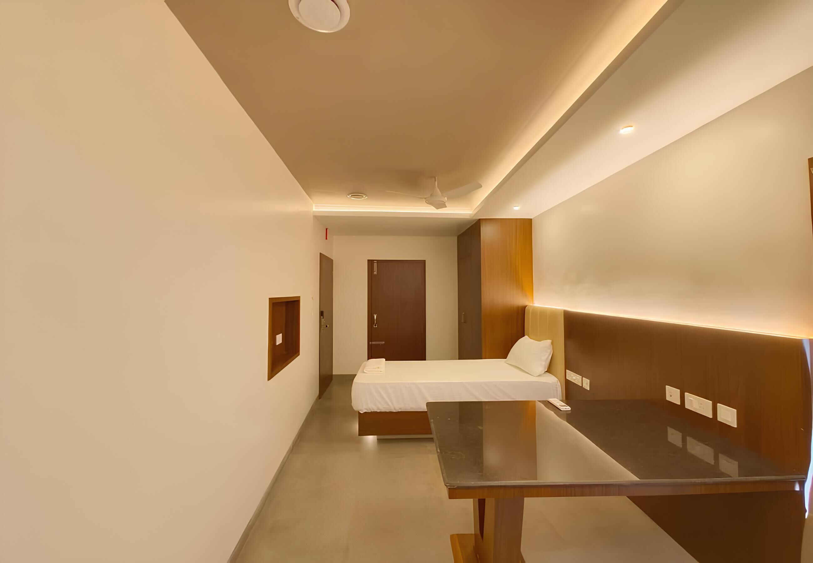 Una habitación de hotel moderna con cama, mesita de noche y ventilador de techo.