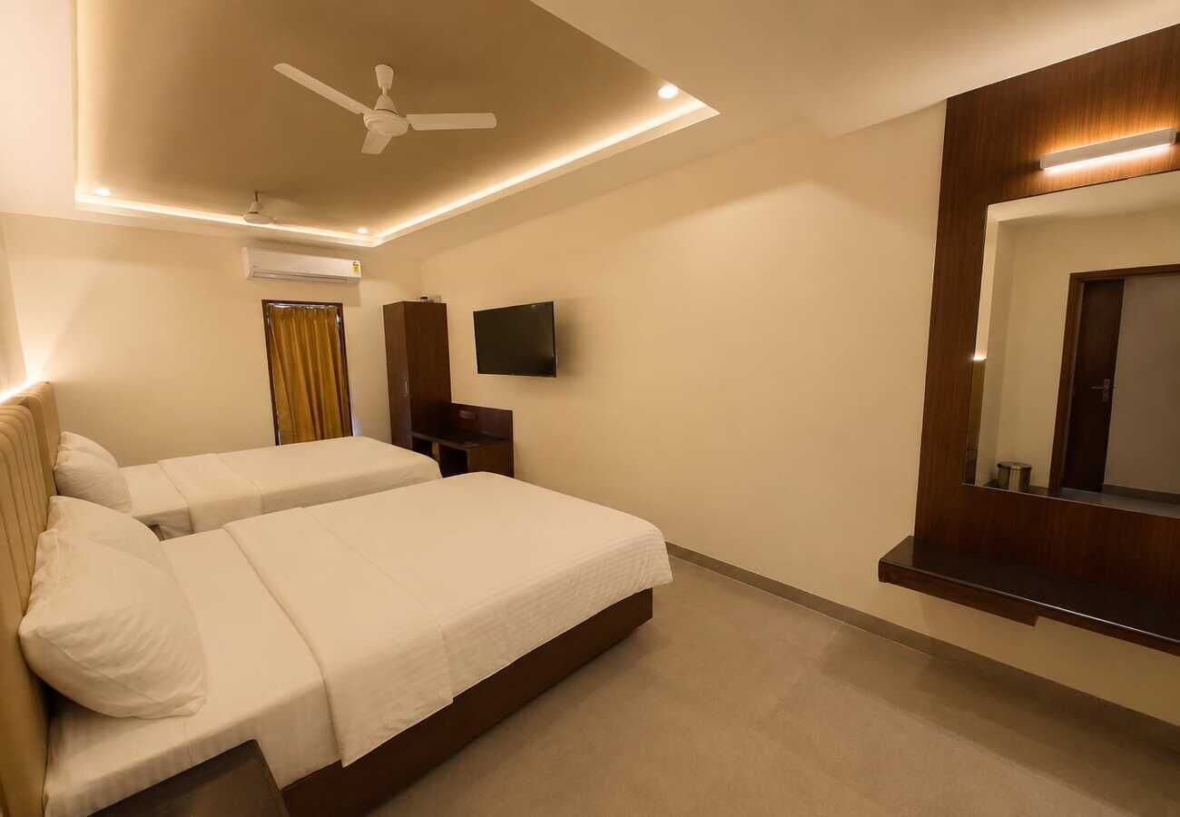A hotel room with two beds, a ceiling fan, a flat-screen TV, and a mirror.