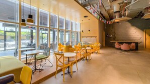 A modern interior with large windows, yellow chairs, and a seating area with a sofa. - Top-Floor Studio Near a Park and Just Minutes by Car from the Mall (Dubai)