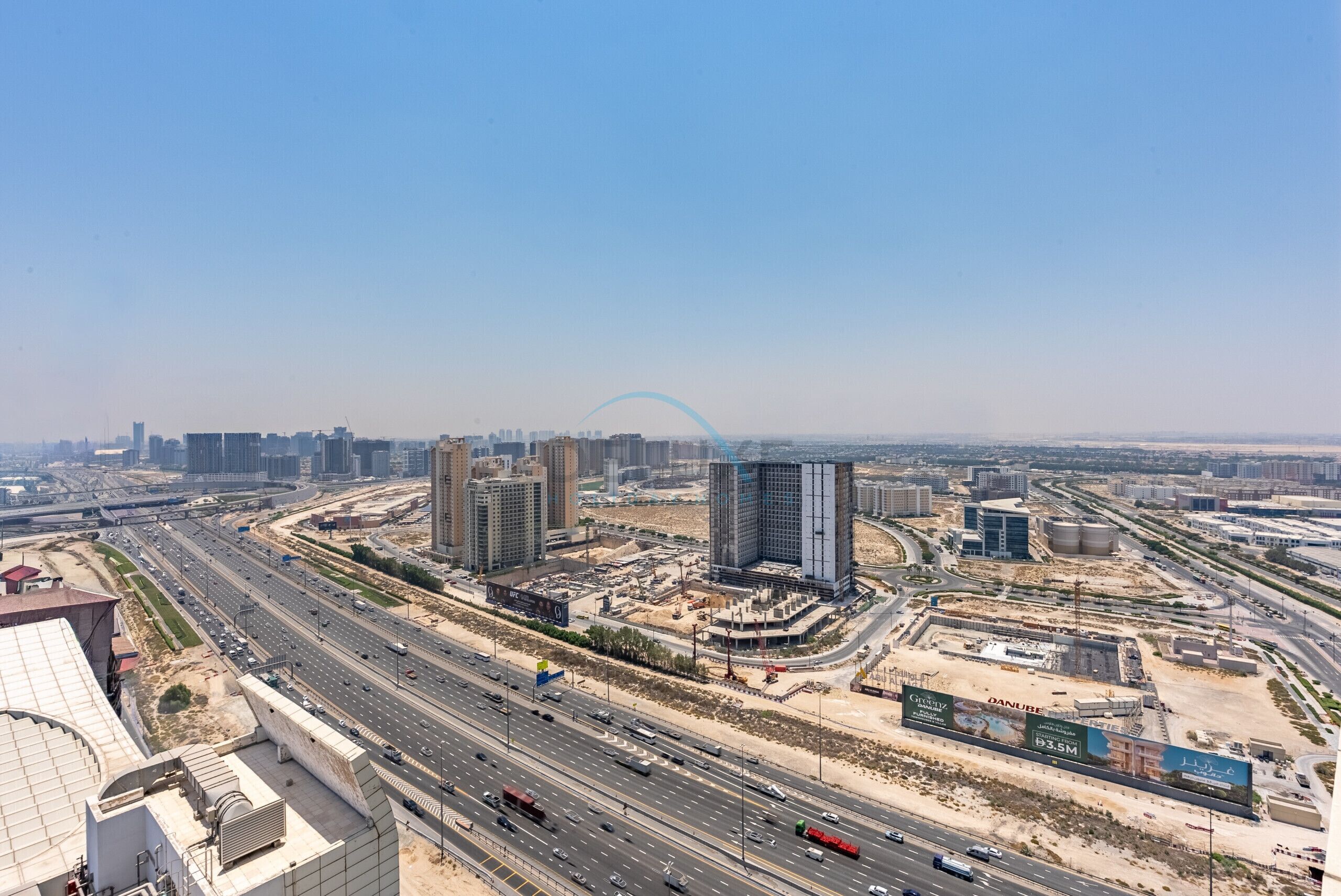 Une vue urbaine comprenant de nombreux immeubles de grande hauteur, une autoroute et des chantiers de construction.