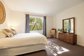 Un dormitorio con cama, cómoda, silla y un espejo grande.