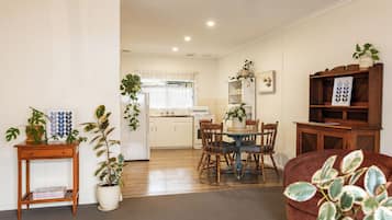 A living room with a dining area, wooden furniture, and potted plants.