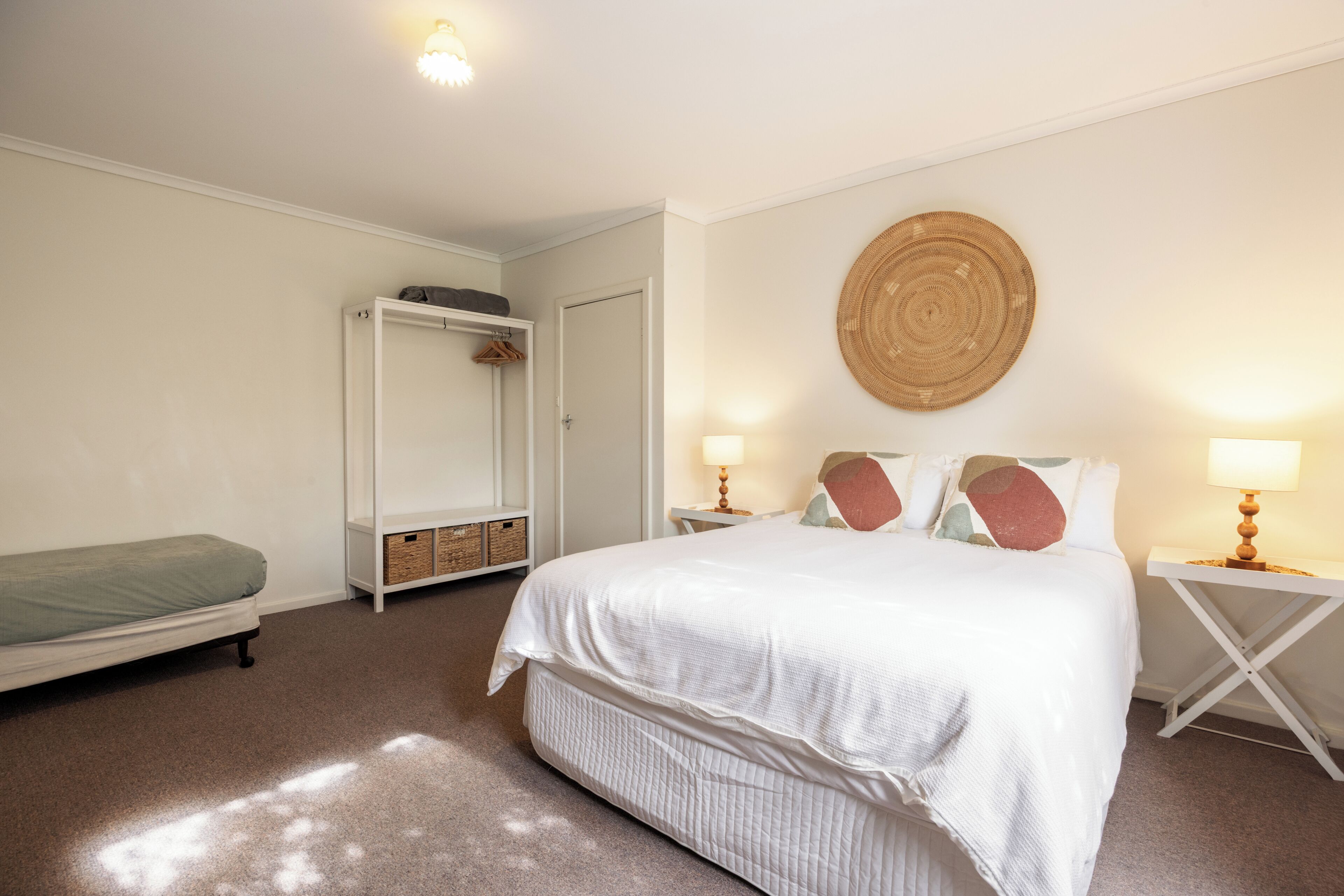 A bedroom with a bed, bedside tables, a wardrobe, and a wall-mounted circular decoration.