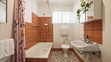 A bathroom with a bathtub, toilet, and sink, featuring a patterned floor and a shower curtain.