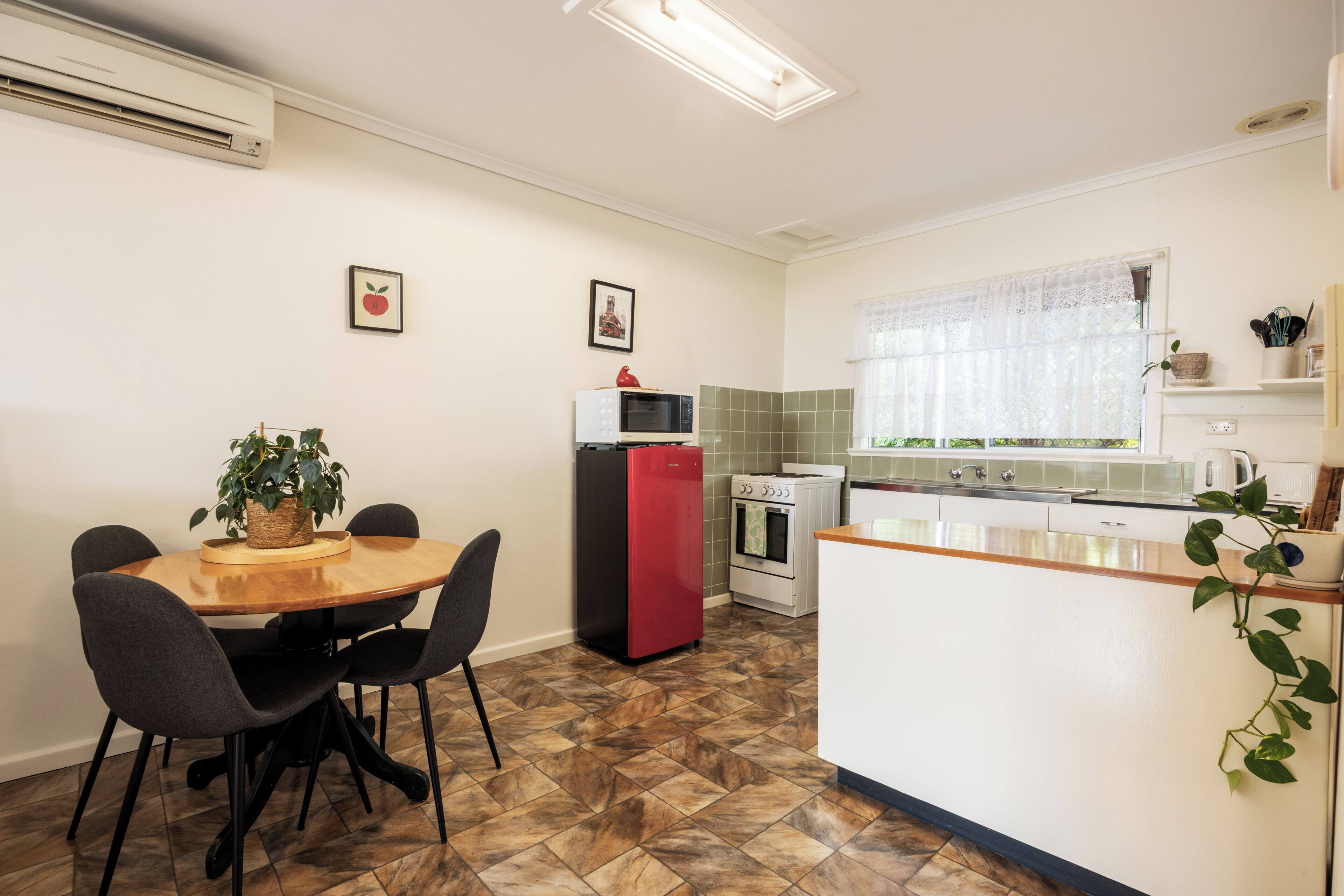 A compact kitchen with a dining area, featuring a microwave, oven, and a small refrigerator.