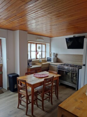 A kitchen with wooden cabinets, a stove, a microwave, and a sink. - Le Jalabio Chalet (Saint-Véran)