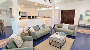 Ein Wohnzimmer mit zwei Sofas, einem Couchtisch und einer Küche im Hintergrund.