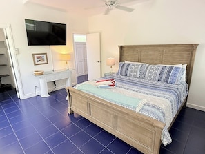 A bedroom with a bed, a desk, a chair, a television, and a door. - Private 3 Bedroom Villa with Pool, Central A/C & Ocean Views in Chocolate Hole, St. John, USVI (St John)
