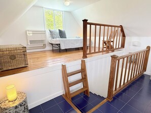 A room with a wooden staircase, a bed with a white bedspread, a window with a view of greenery, and a small table with a lamp. - Private 3 Bedroom Villa with Pool, Central A/C & Ocean Views in Chocolate Hole, St. John, USVI (St John)