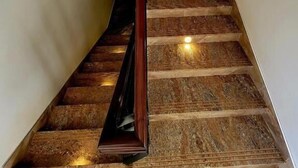 A staircase with a handrail, carpeted steps, and a light fixture on the wall.