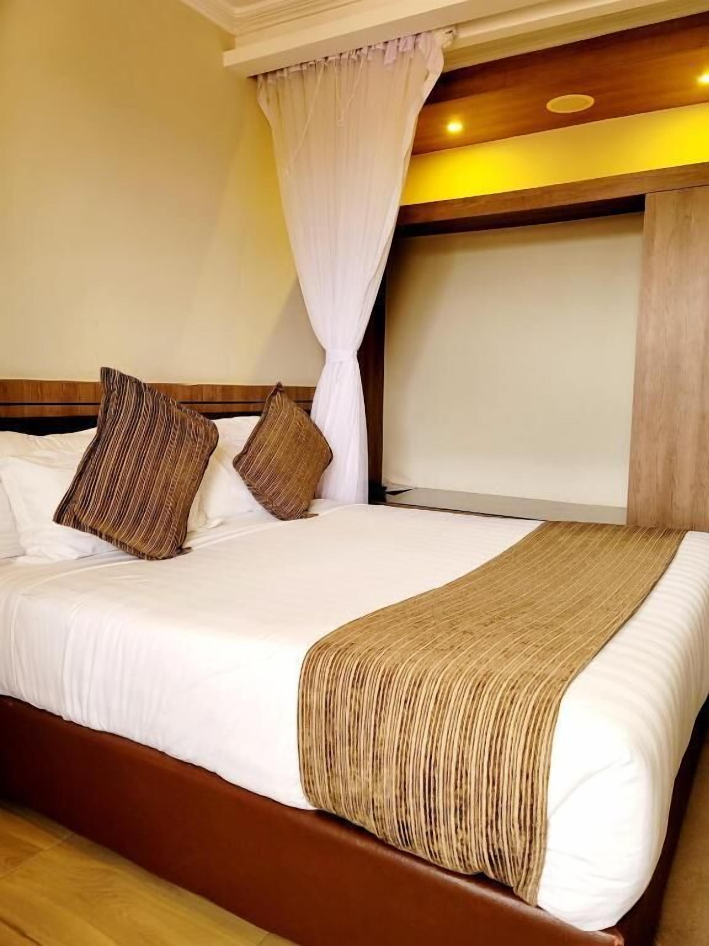 Una habitación de hotel con una cama grande, cabecera de madera y dosel.