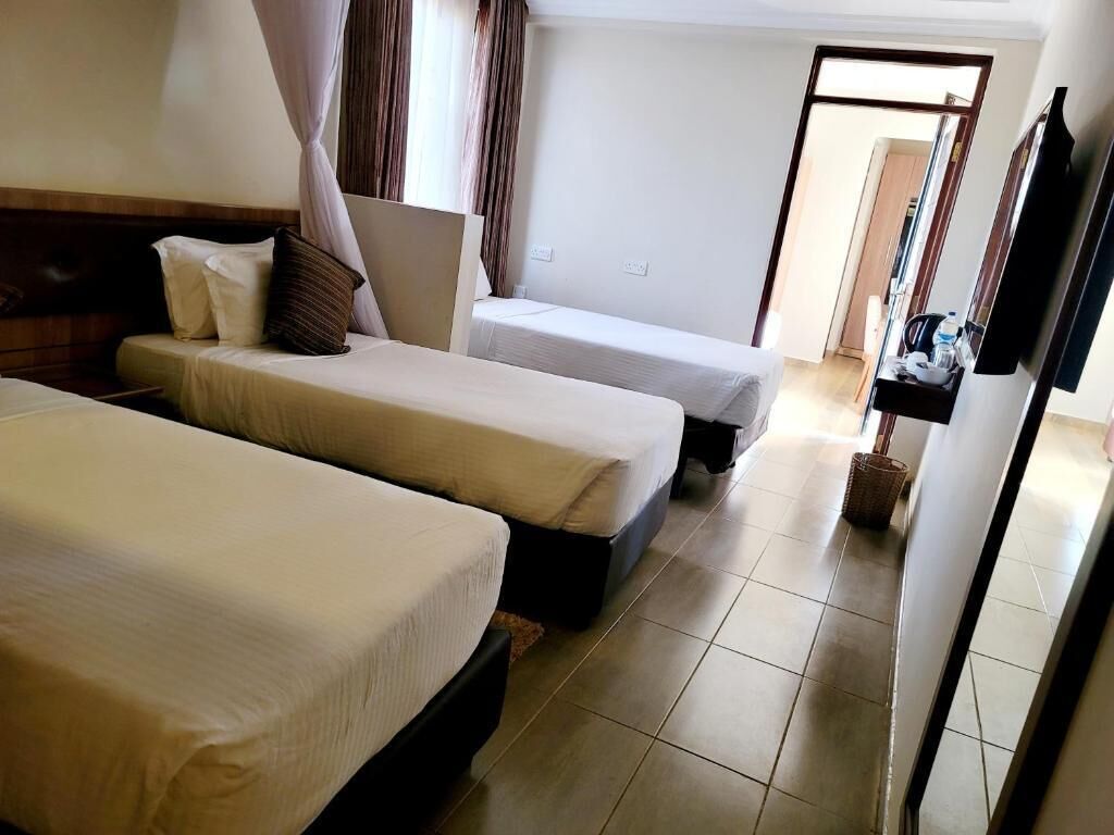 Habitación de hotel con dos camas, un televisor de pantalla plana, una mesita y un armario.