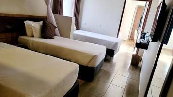 Habitación de hotel con dos camas, un televisor de pantalla plana, una mesita y un armario.