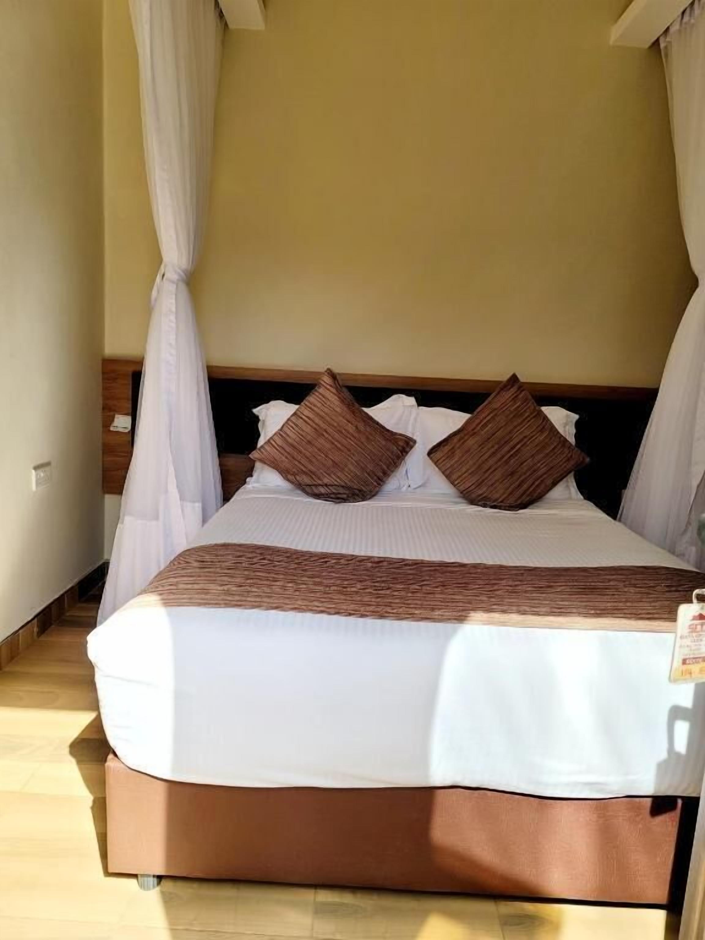 Una cama con cabecera de madera, ropa de cama blanca y dos almohadas marrones.