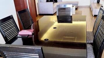 Un comedor con una mesa de vidrio, sillas negras, un sofá y un televisor en la pared.