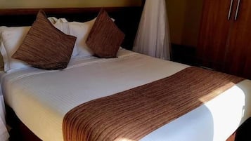 Una cama con colchón blanco, almohadas marrones y una manta marrón.